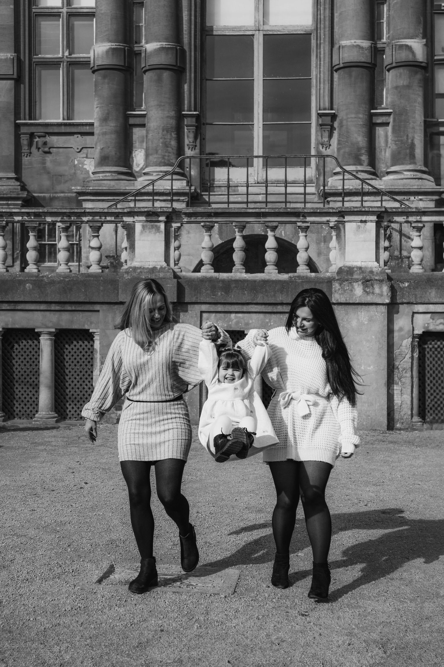 Black and white photo showing Mum and Grandmother in white sweater dresses walking together outside a historic building, in Nottingham