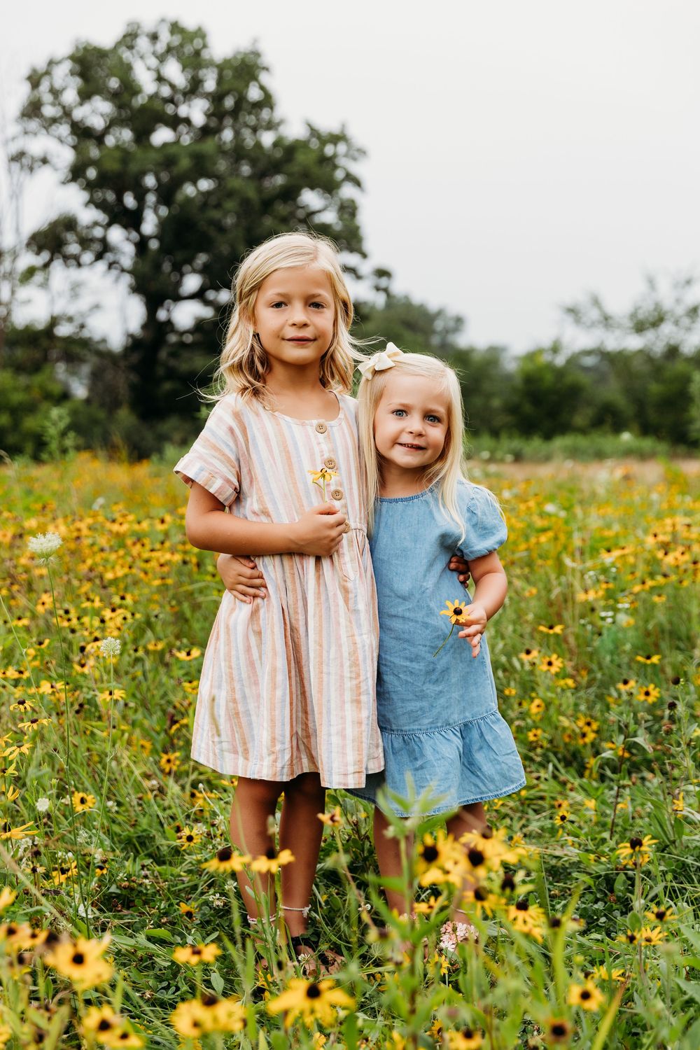 Children embracing in a meadow filled with bright yellow wildflowers and green grass.
