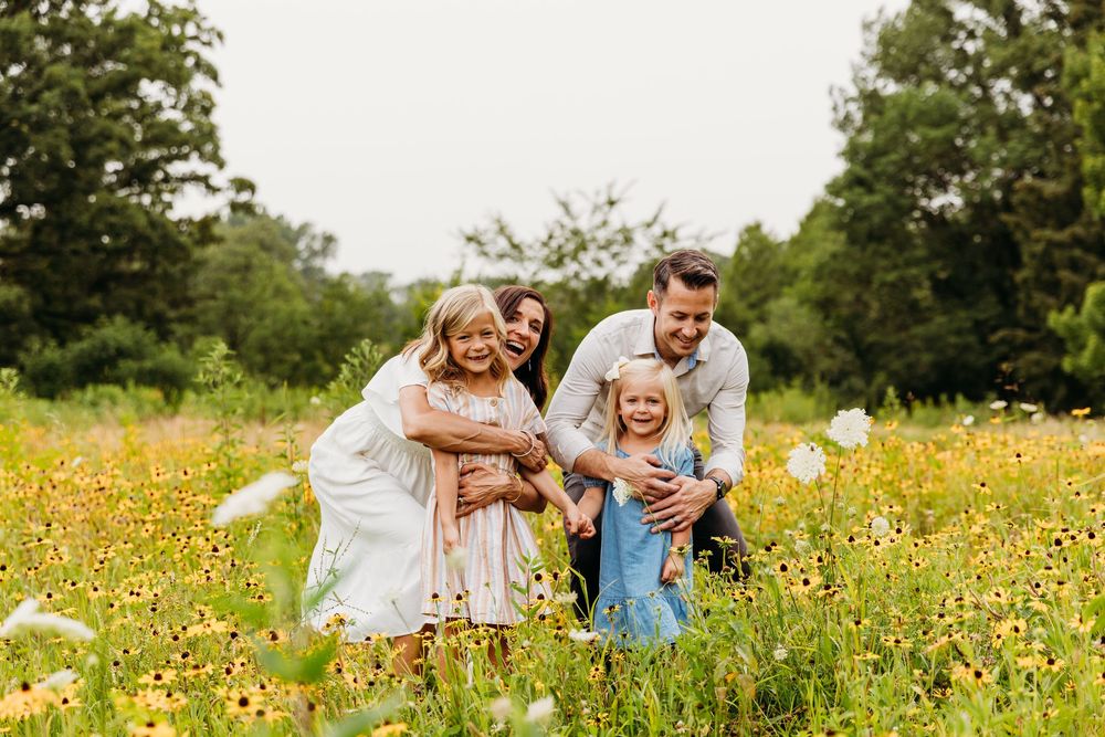 A candid family moment captured in a field of yellow wildflowers during golden hour.