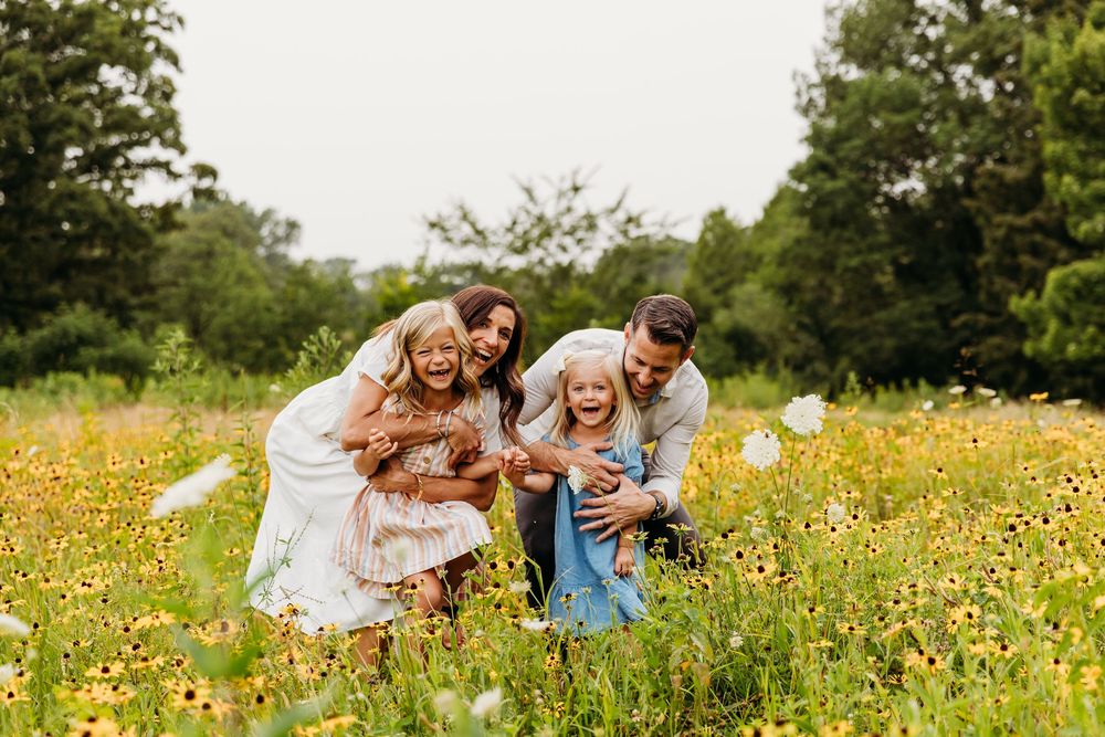 Playful family interaction among yellow wildflowers in a natural outdoor setting.