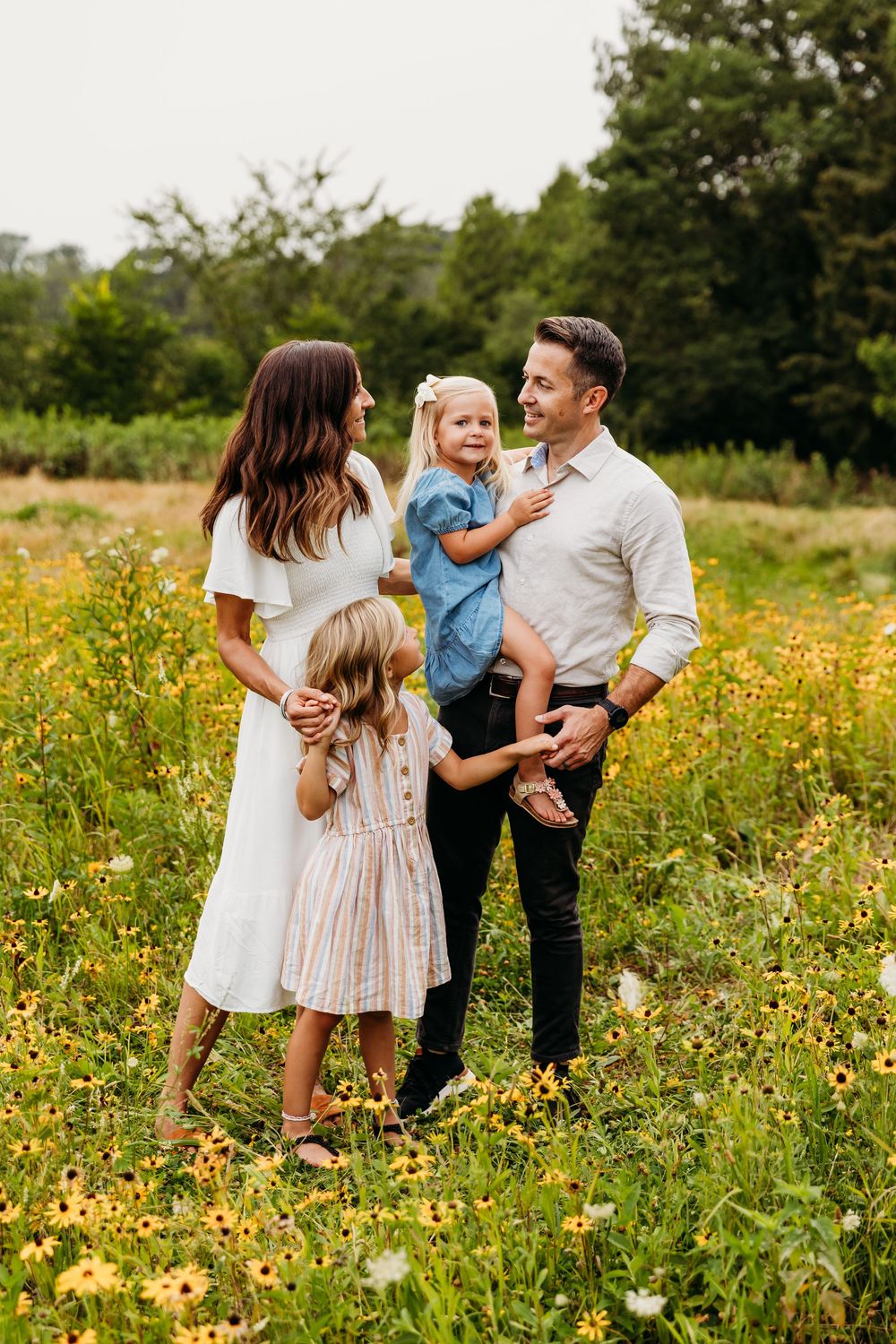 Casual family photoshoot in a meadow with yellow flowers and natural greenery.