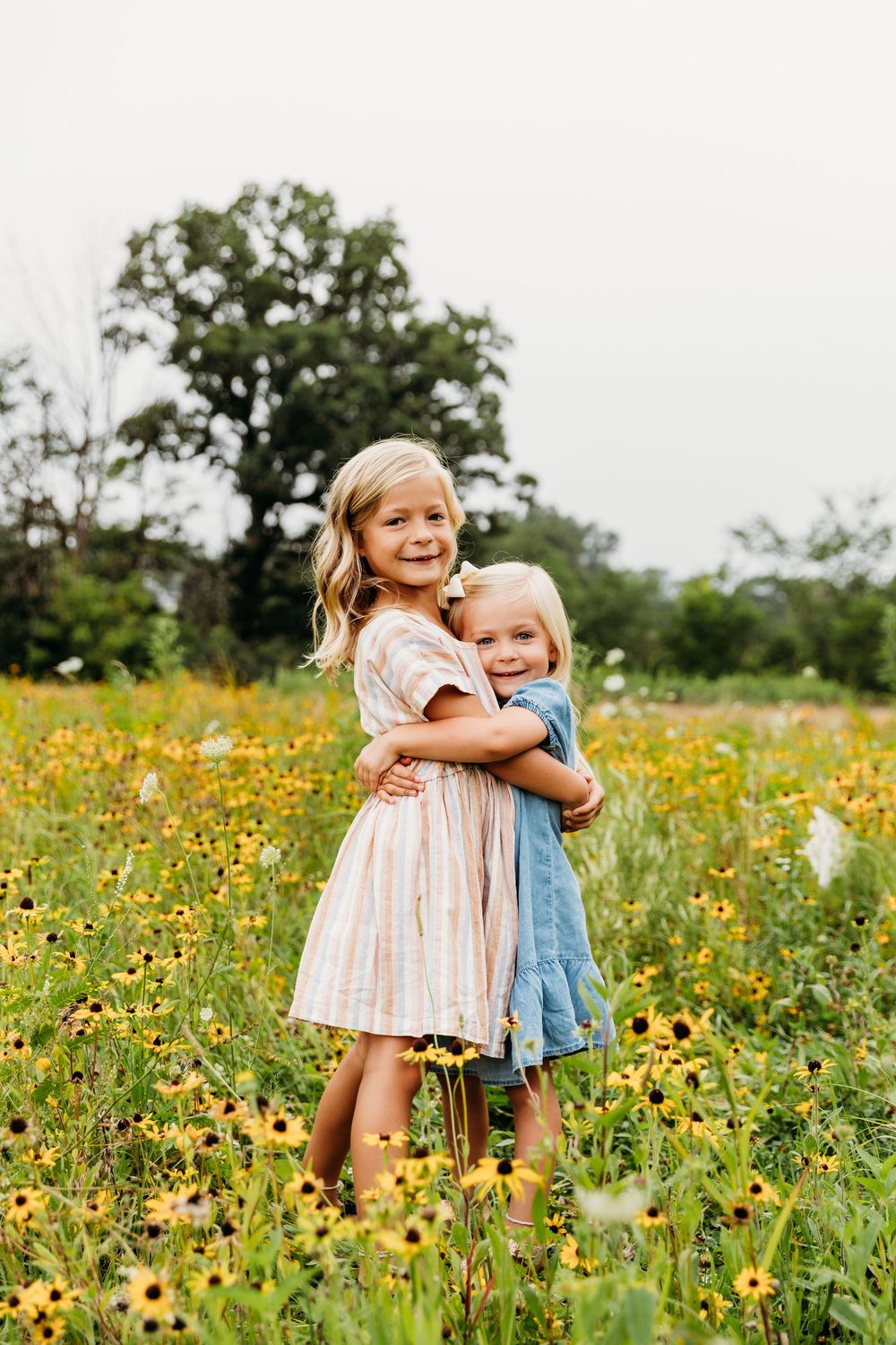 Two small figures share a joyful hug while standing in a field of blooming sunflowers.