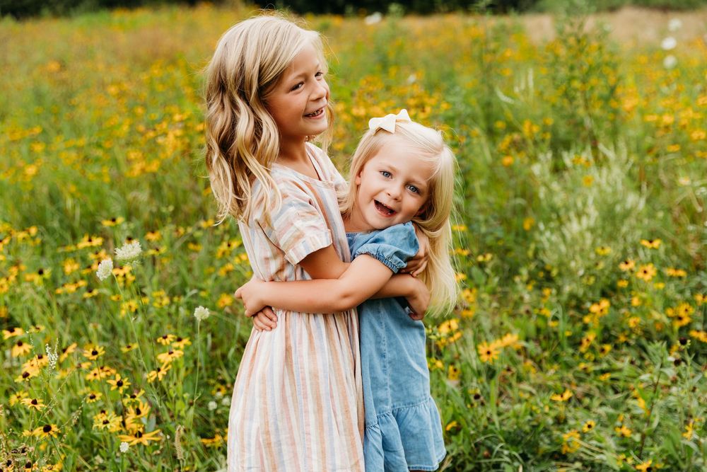 Children playing and laughing together in a meadow filled with yellow wildflowers.