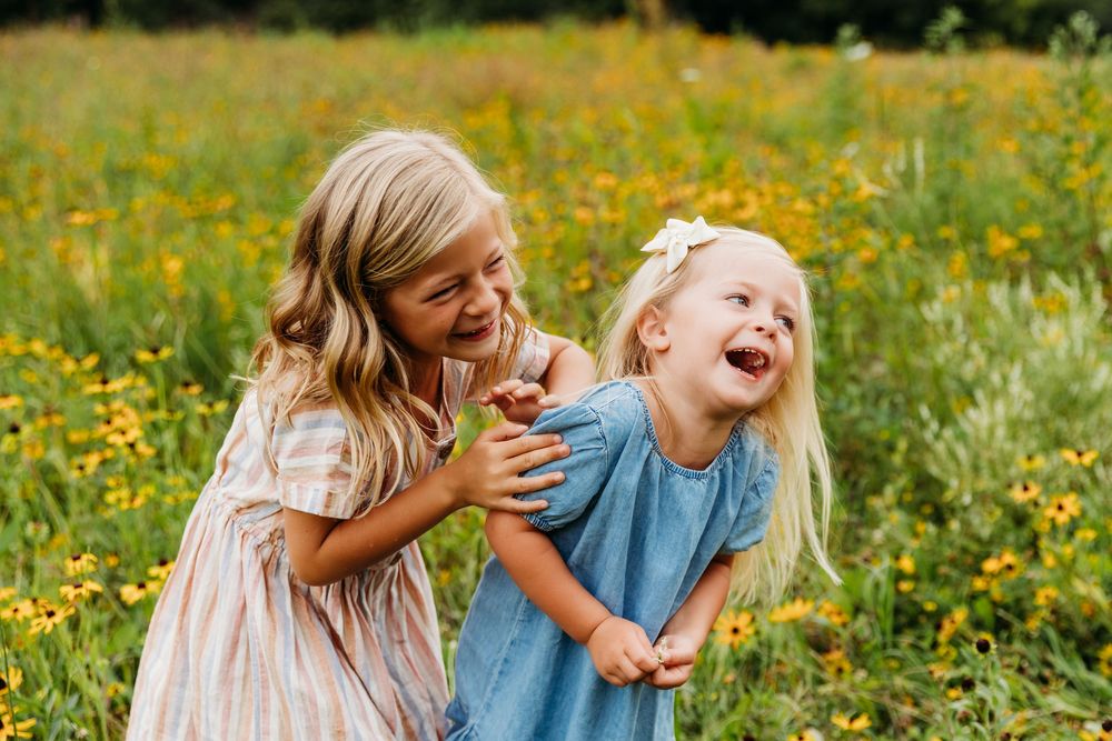 Candid moments of joy captured between two small figures in a sunflower-filled field.