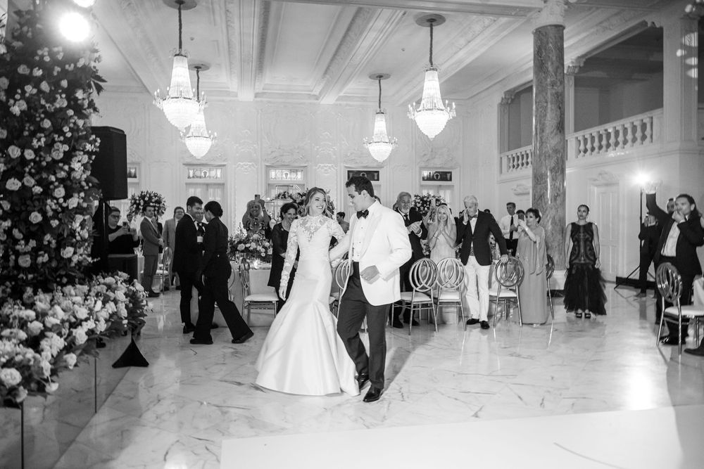 Couples dance at an elegant black and white wedding reception with chandeliers and a decorated Christmas tree.
