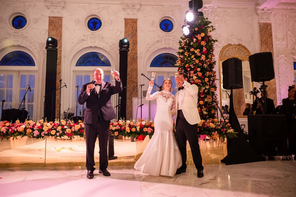 A festive wedding reception scene with performers on stage in front of a decorated Christmas tree in an elegant ballroom.