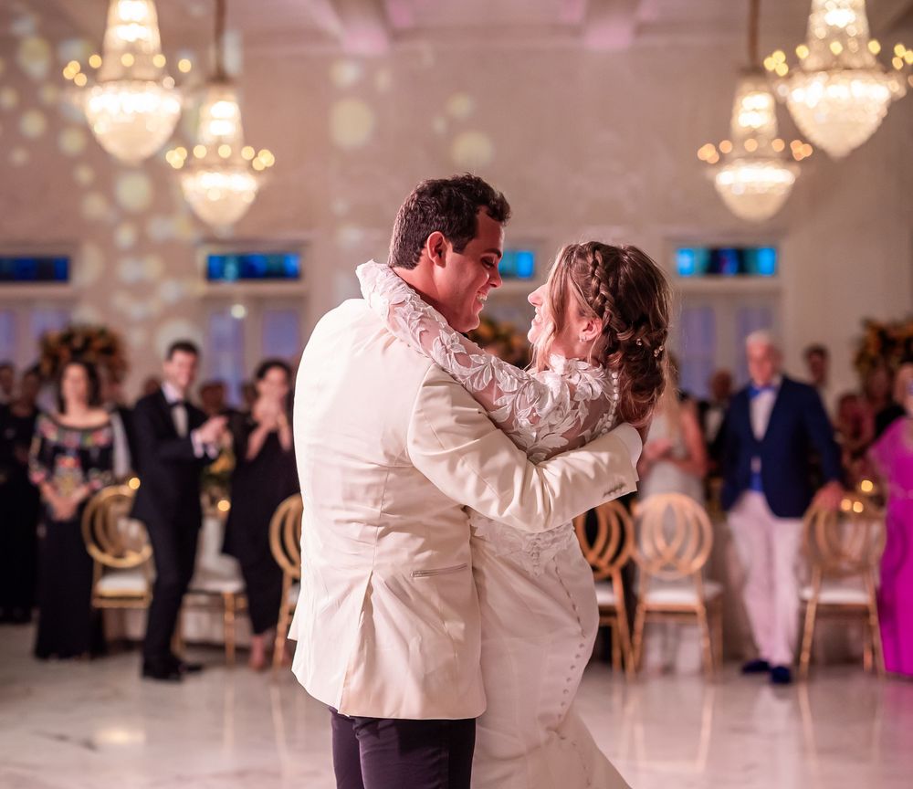 A couple shares their first dance at a wedding reception in an elegant ballroom with crystal chandeliers.