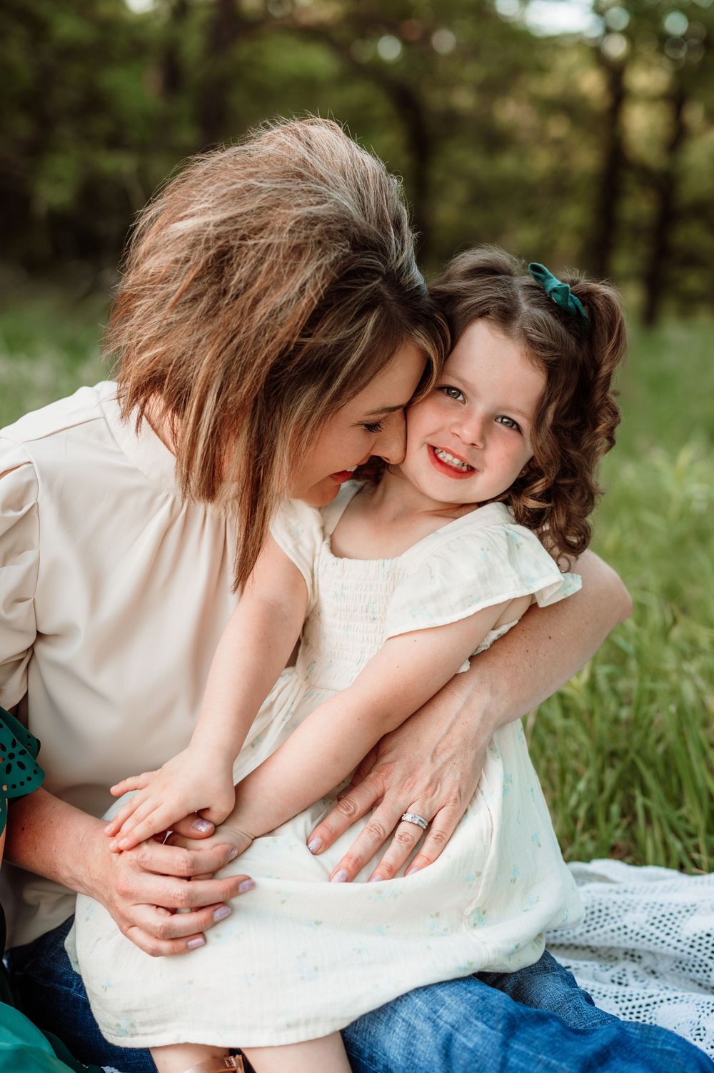 A tender moment shared between parent and child sitting together on a blanket in a sunny meadow during summer.