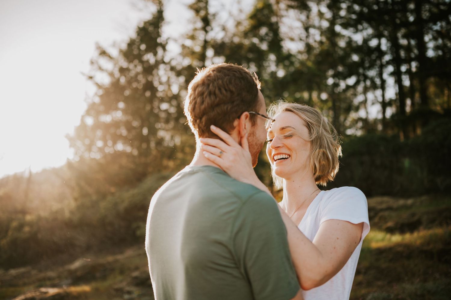 Candid laughter between couple on the cliffs of Comox Lake Bluffs. Golden hour light photography taken by Vancouver Island photographer