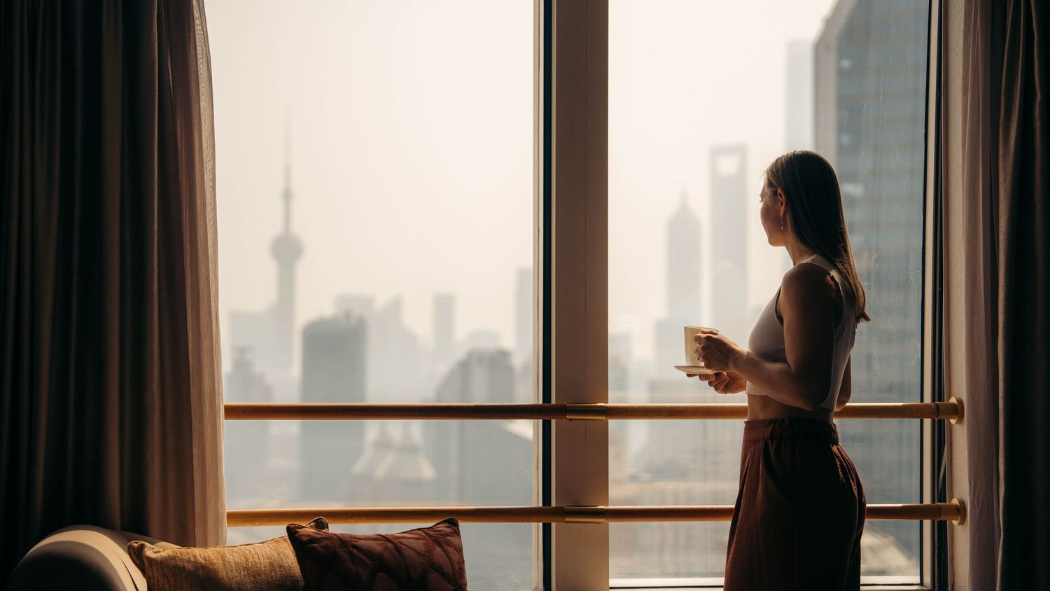 Woman in a hotel suite with a view of the Shanghai skyline