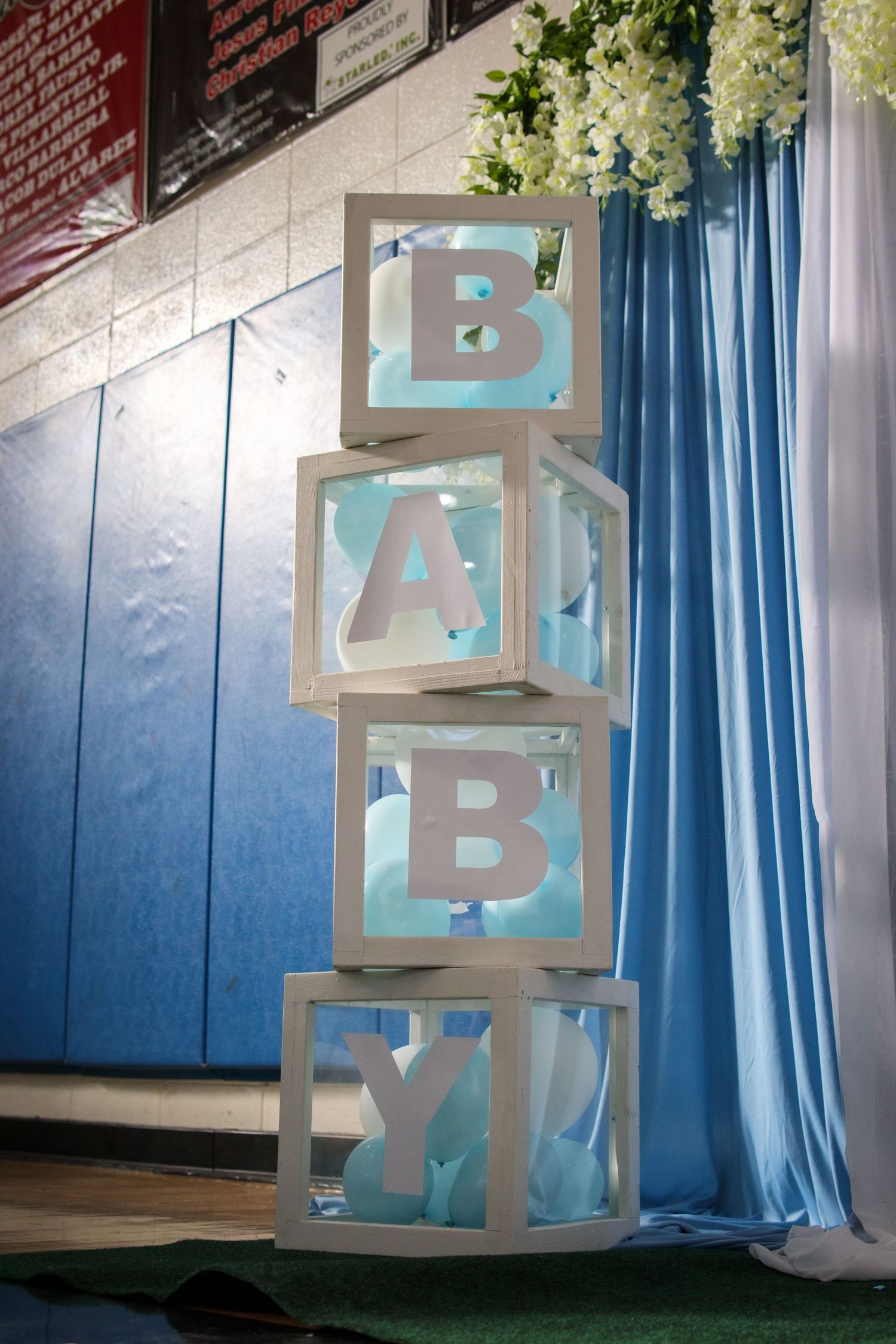 Decorative stacked white baby blocks spelling BABY with blue accents at a baby shower.