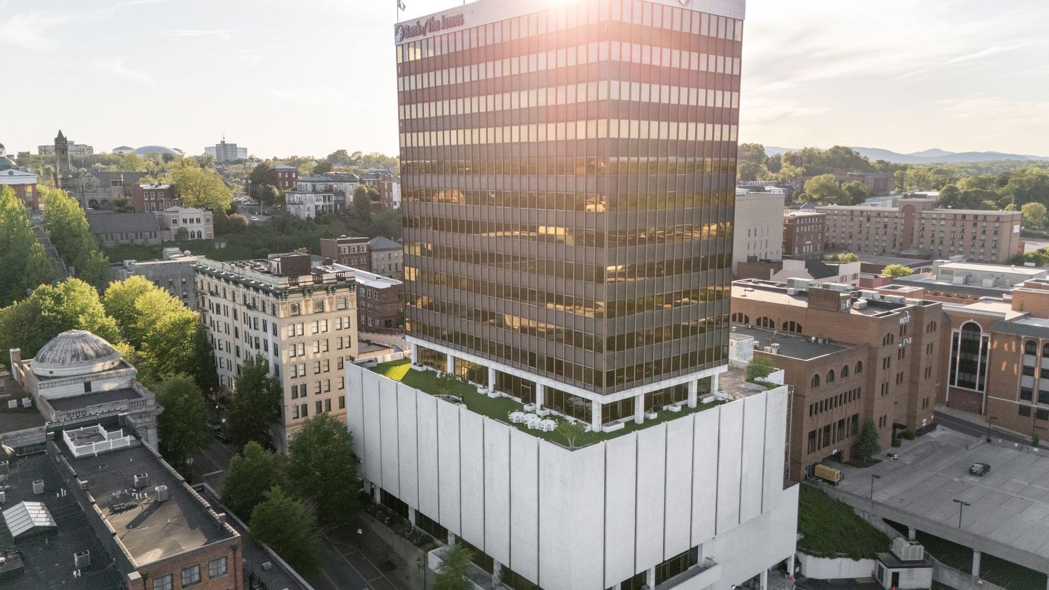 Modern glass office building reflecting sunlight in an urban cityscape.