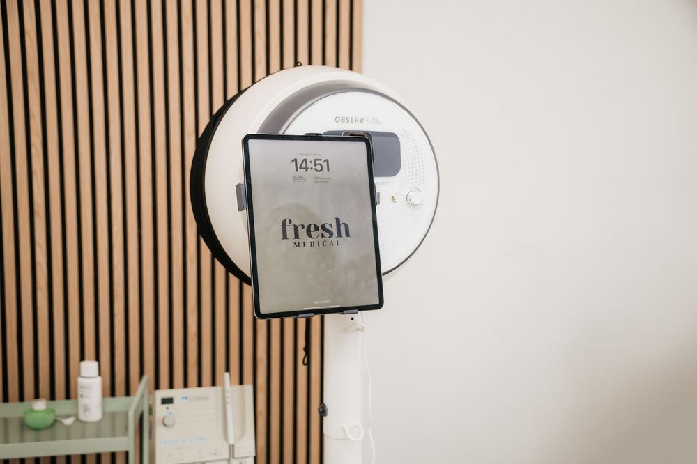 A modern electronic hand dryer mounted on a wall with vertical wooden slats features a Fresh brand display screen.