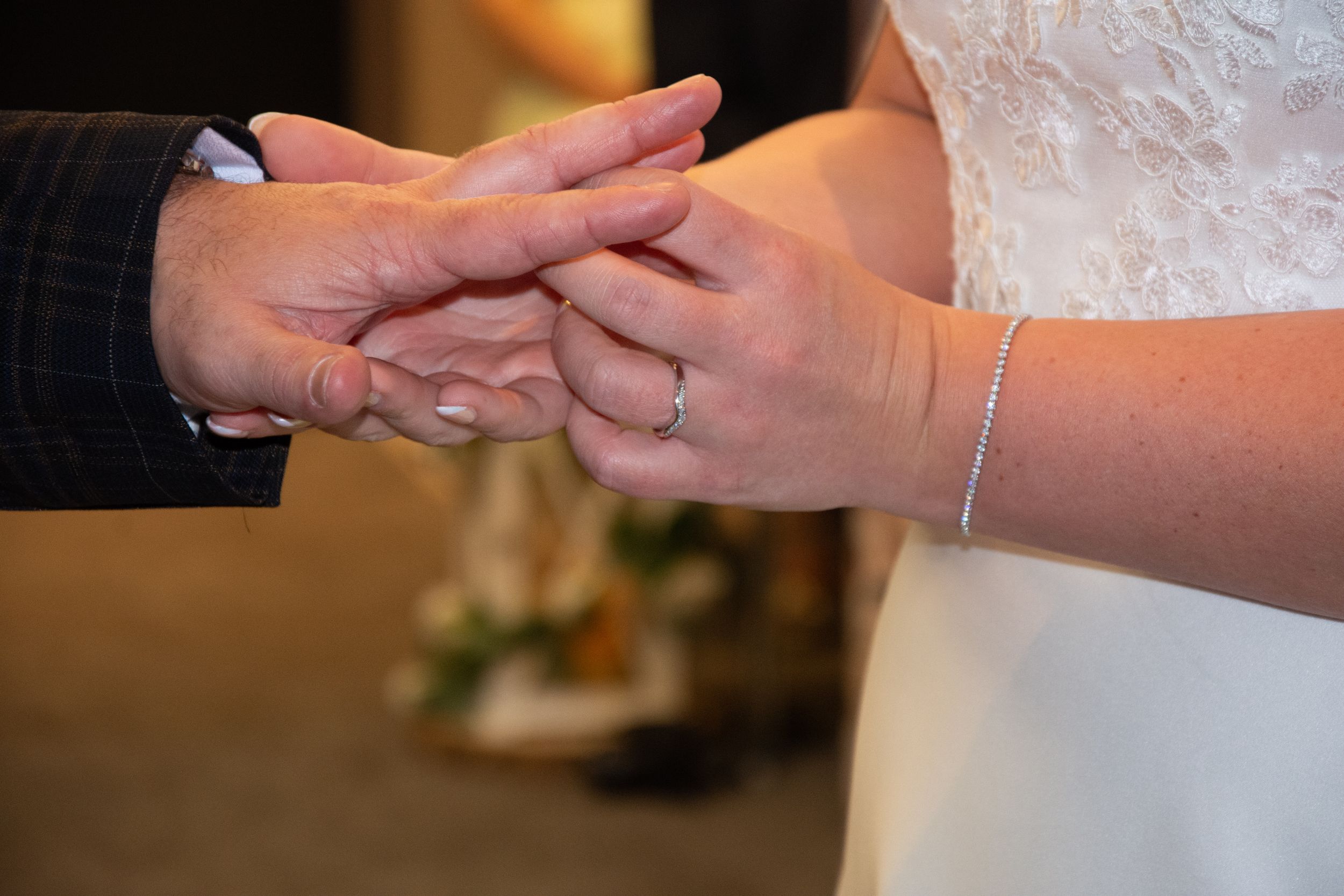 Close-up of hands exchanging wedding rings during a marriage ceremony.