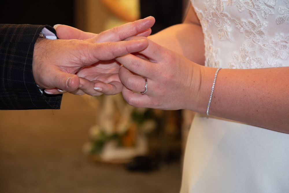 Close-up of hands exchanging wedding rings during a marriage ceremony.