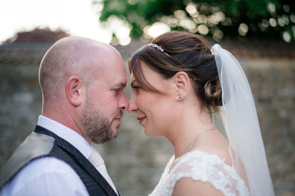 Close-up of a tender moment between newlyweds, with bride in white lace gown and veil.