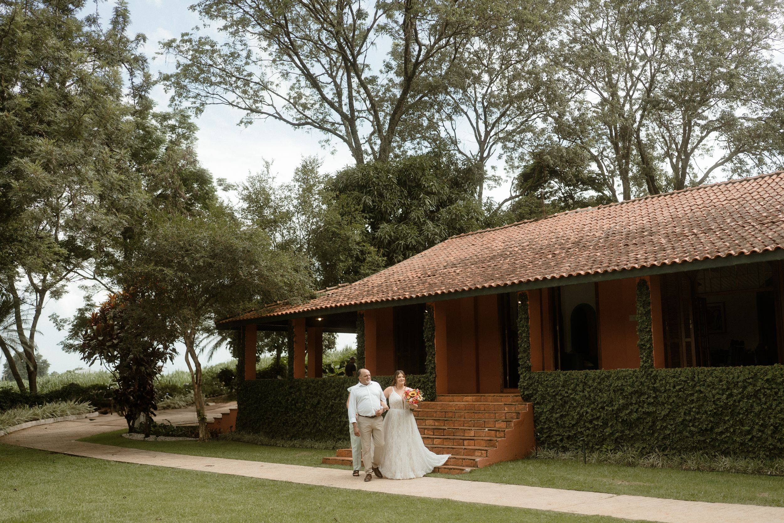 Rustic brick building with covered porch surrounded by green landscaping.