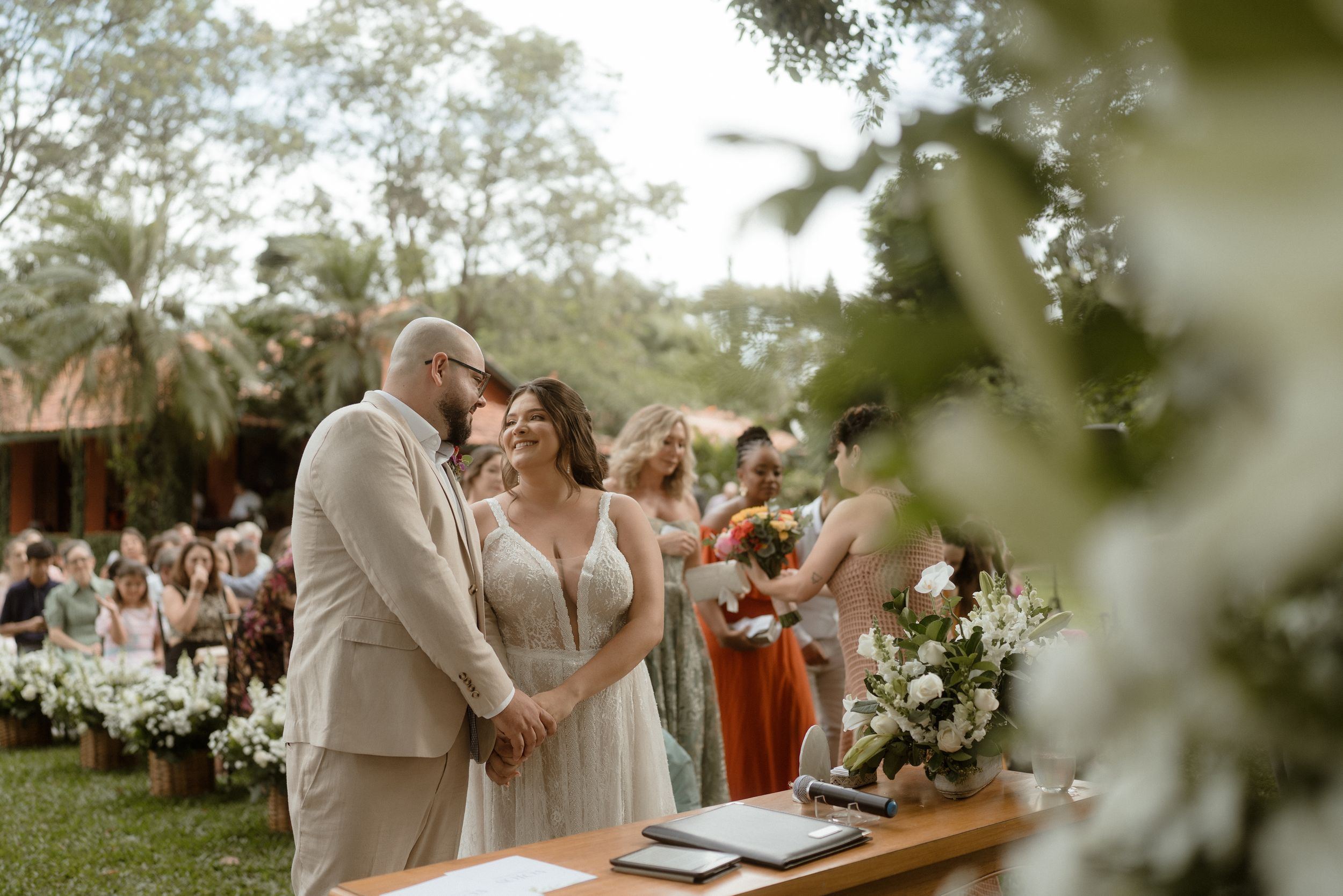 An emotional moment during an outdoor wedding ceremony with guests seated on white chairs.