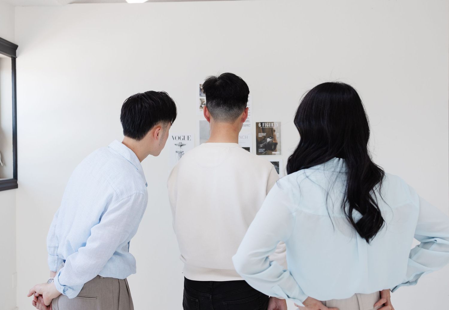Three people looking at wall display in modern office setting.