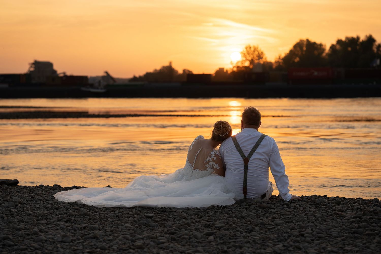 Hochzeitspaar am Goldkanal bei Rastatt, barfuß am Sandstrand mit Blick auf das Wasser und Sonnenuntergang.