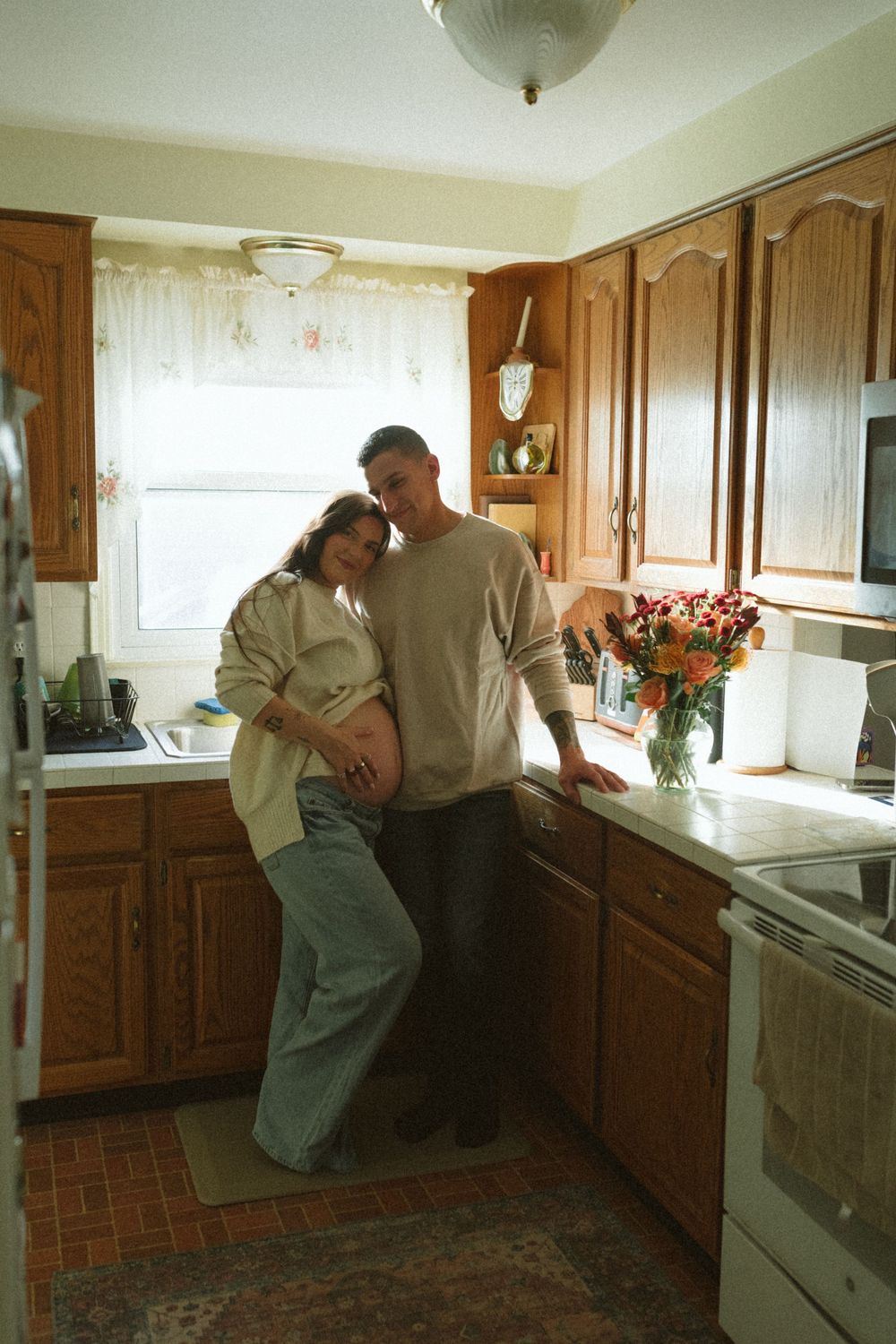 Three sequential images show a couple dancing together in a kitchen with wooden cabinets and natural lighting.