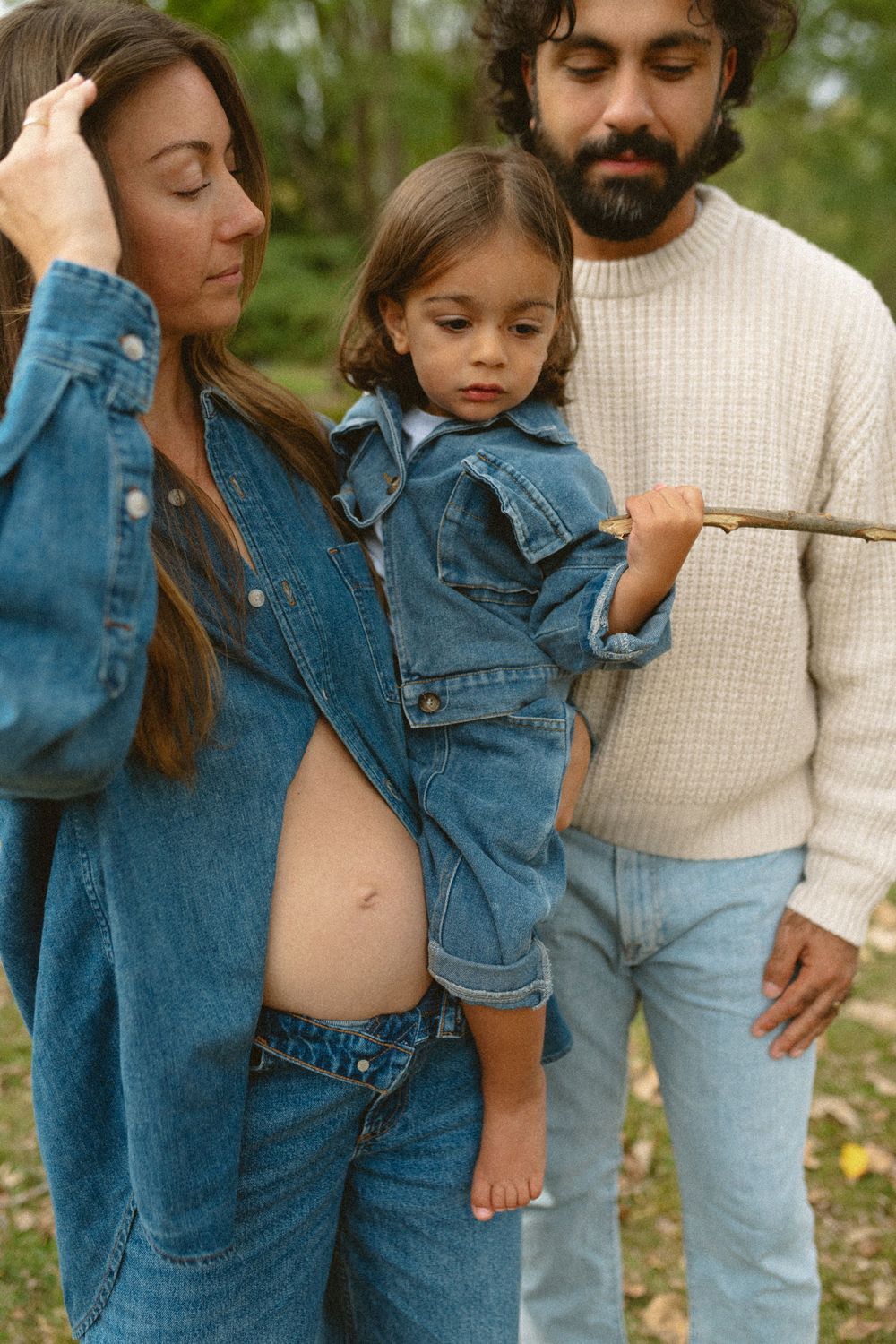 Family wearing denim and cream sweater poses together outdoors in a series of casual lifestyle photos.