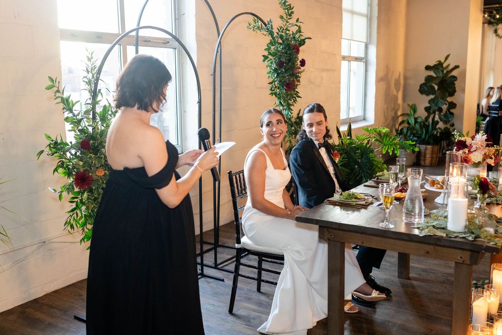 A celebratory wedding reception scene with candlelit table decorations and greenery at an elegant indoor venue.