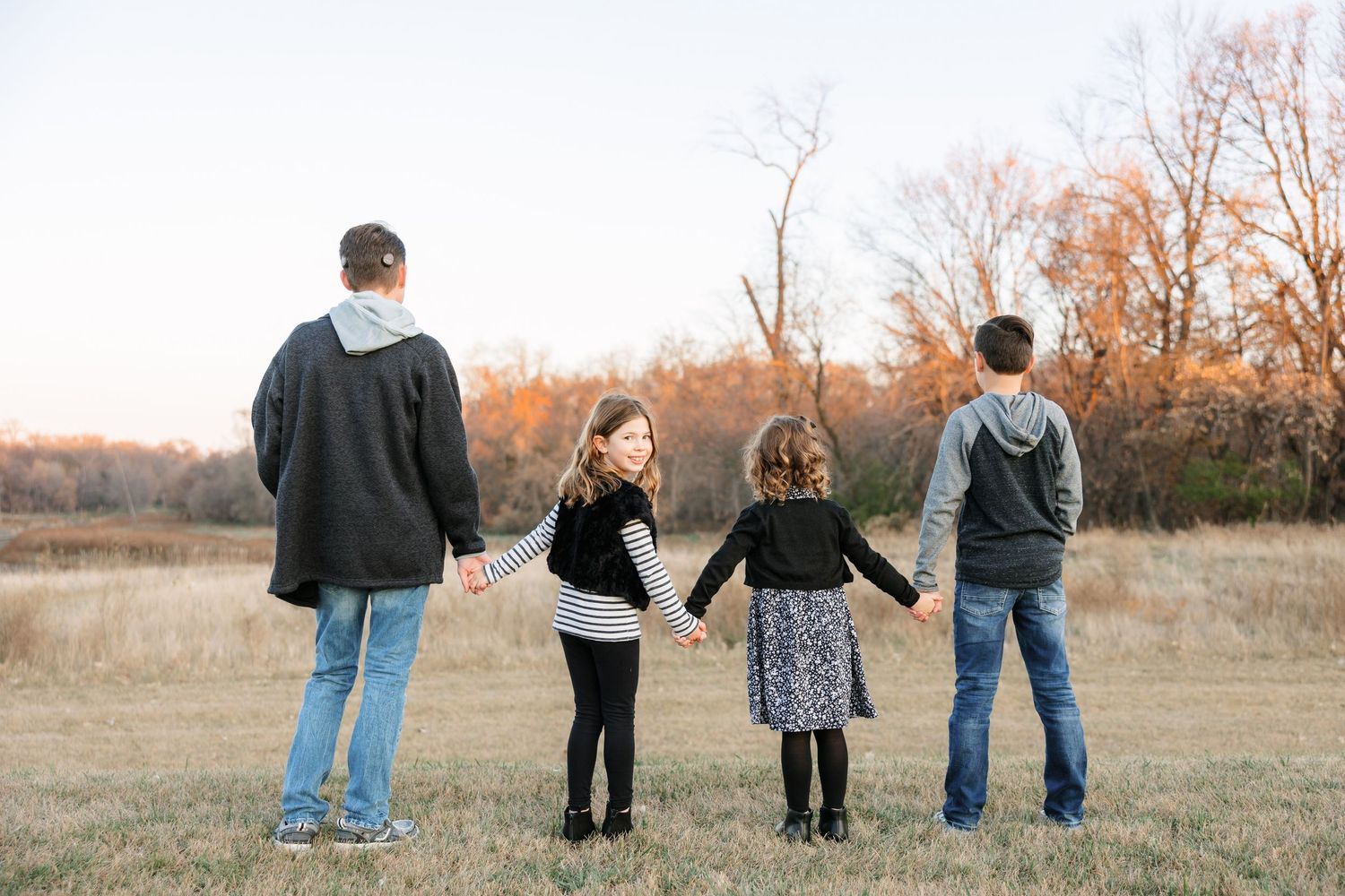 Multi-generational family portrait taken outdoors in autumn with fall foliage and natural landscape backdrop.