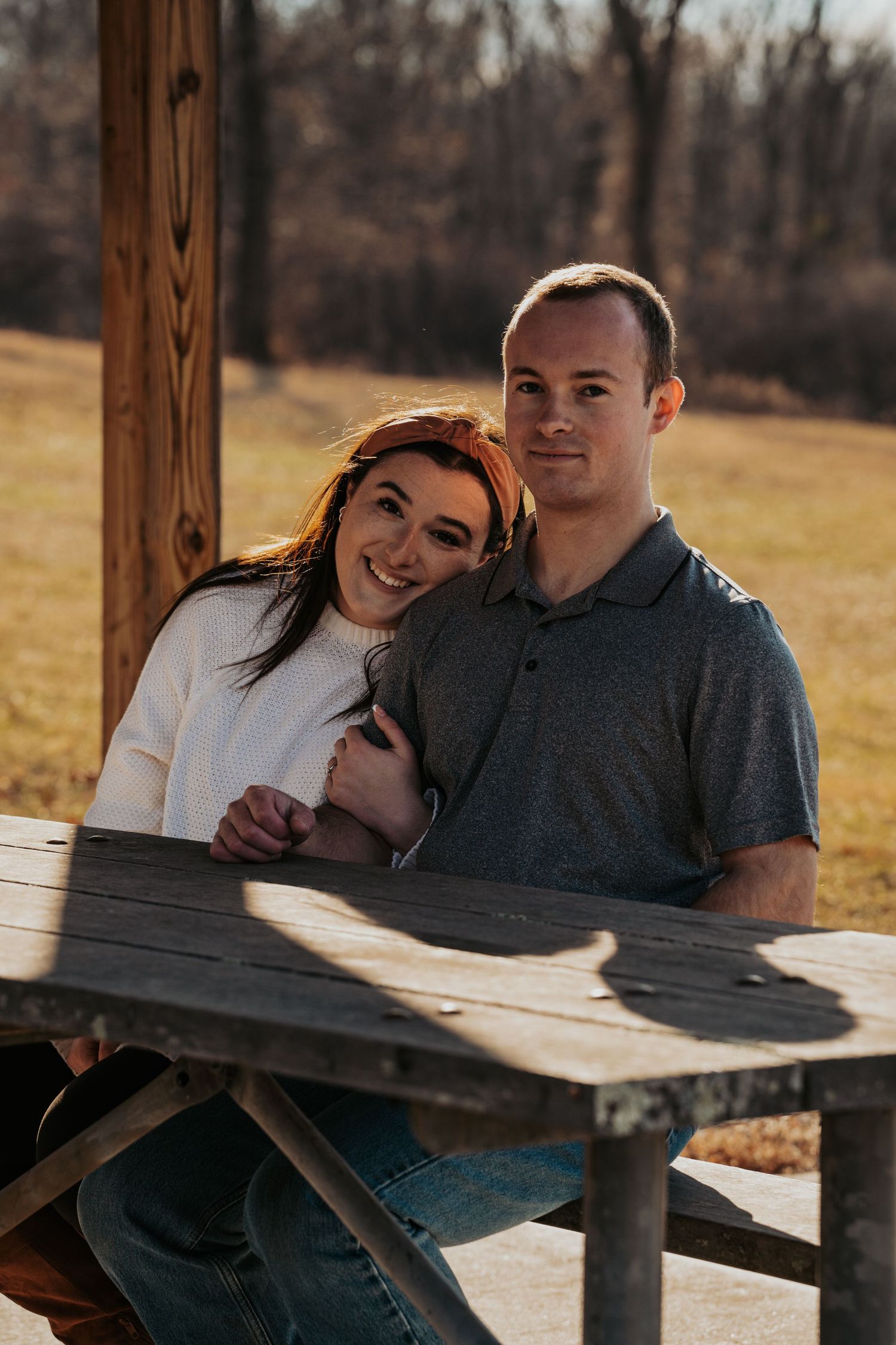 Newly engaged smiling and holding hands at rustic outdoor table