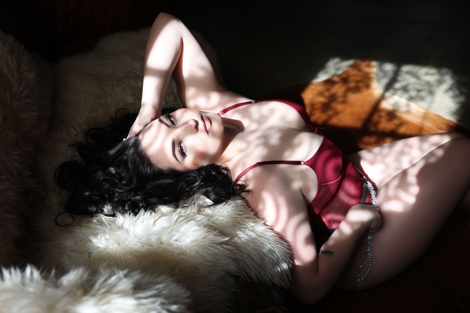 Woman posing at the edge of a couch in moody lighting boudoir session