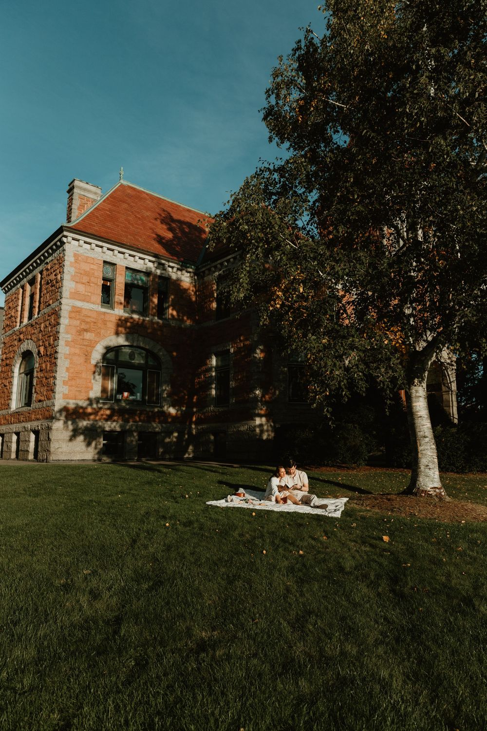 A stone building sits atop a grassy hill on a sunny autumn day.