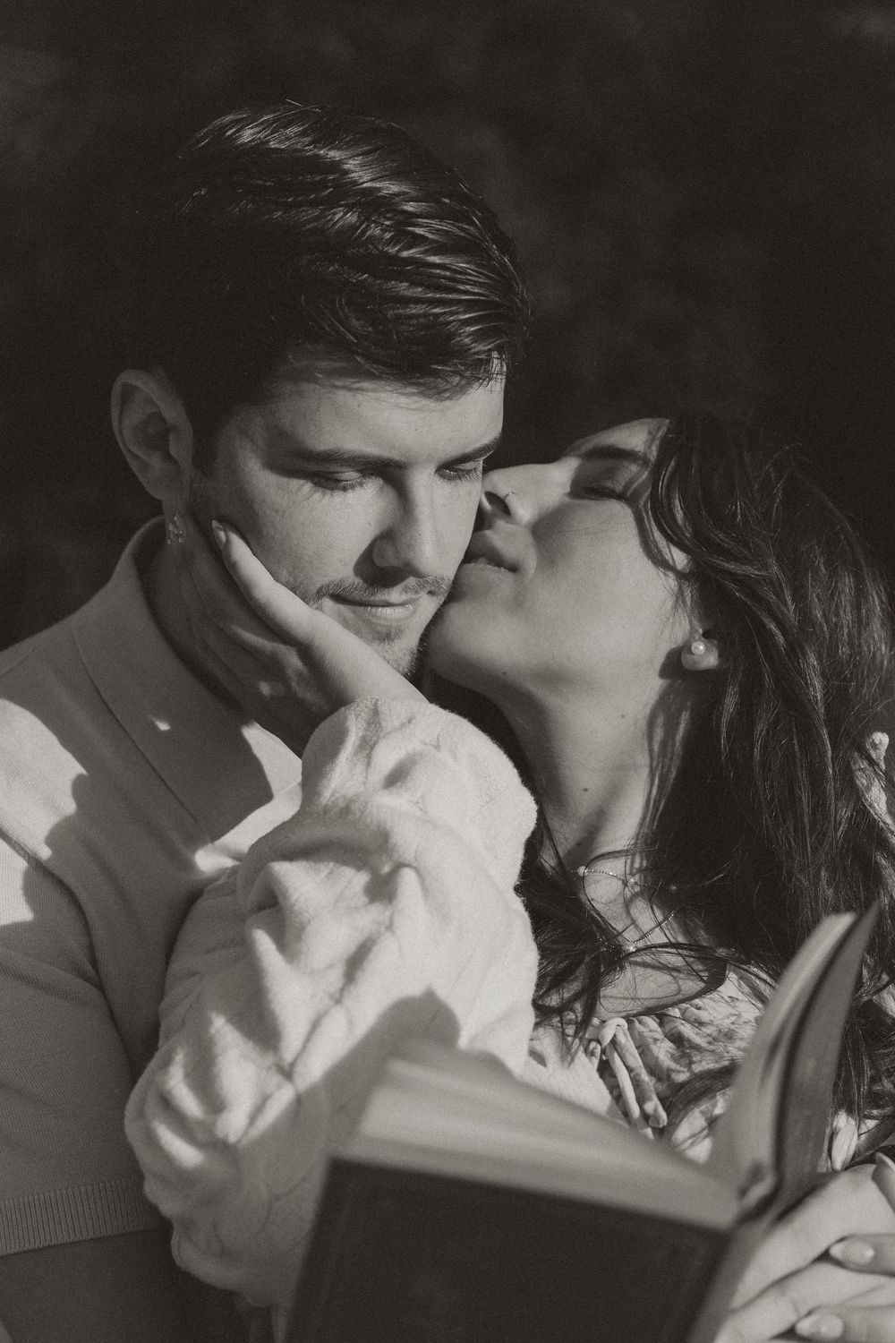 An intimate black and white portrait of a couple sharing a tender moment.