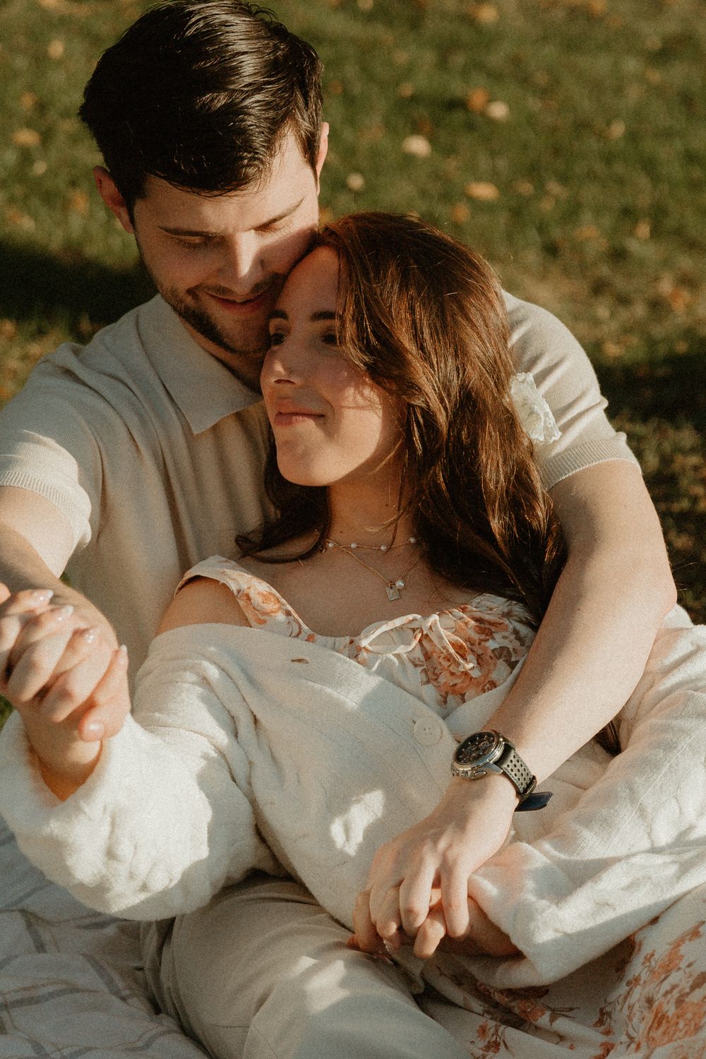 A romantic couple in white clothing shares an intimate moment during a sunset photoshoot.