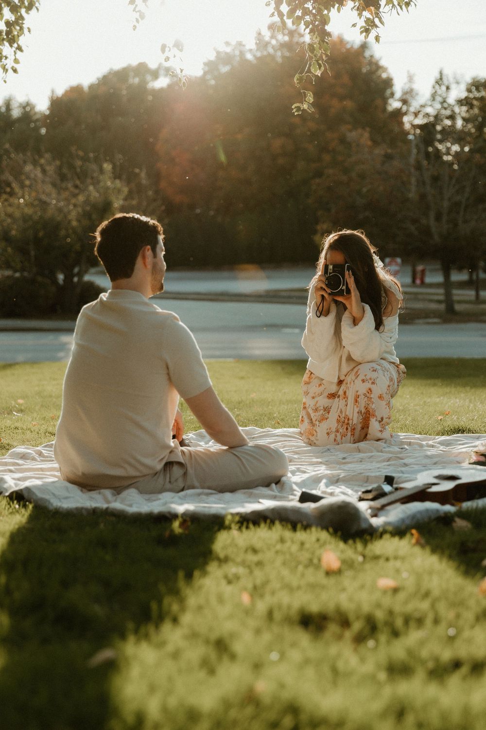 Two people share an intimate moment during a golden hour picnic in a park setting.