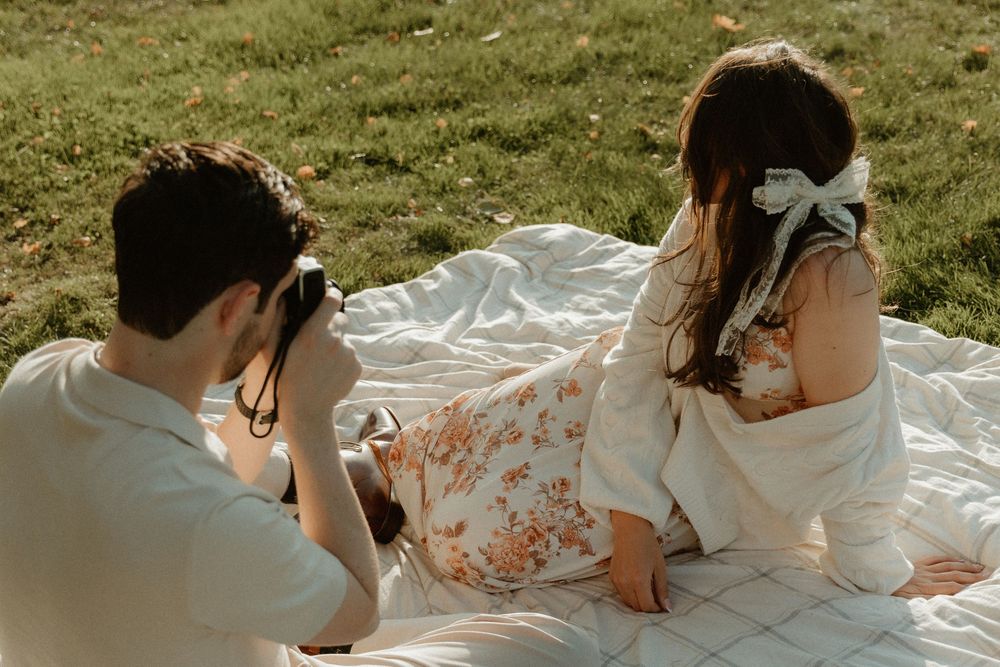 A photography session takes place on a white blanket during a sunny afternoon outdoors.