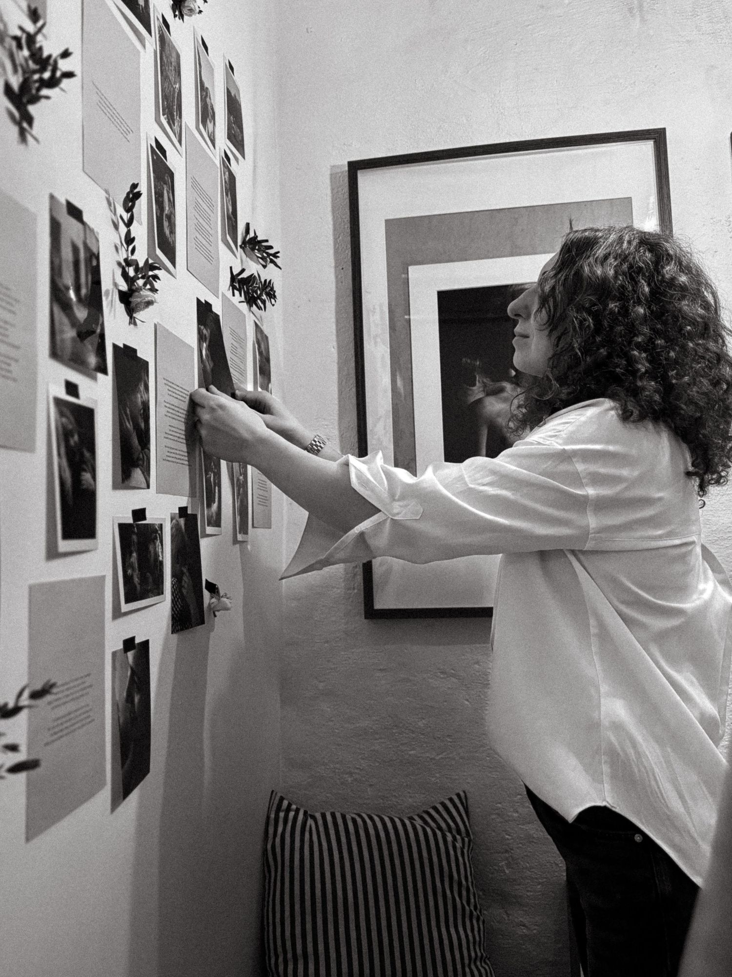 family photographer in Stockholm arranging photo wall for her photography exhibition in Vasastan
