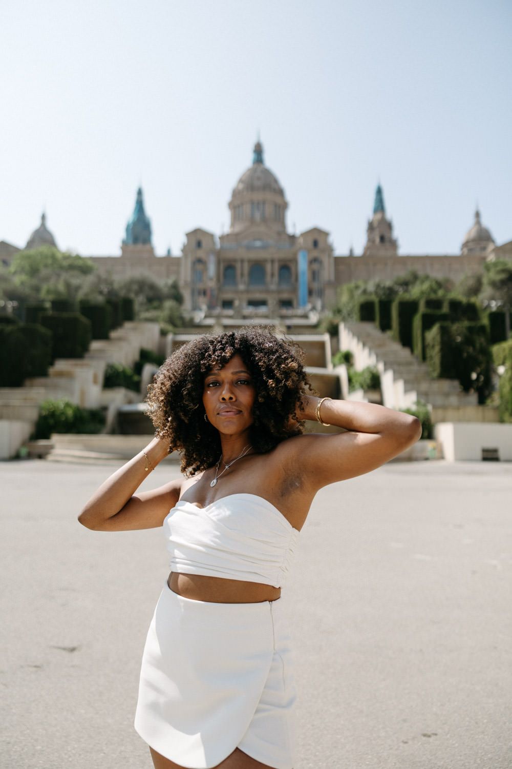 Dance-inspired poses in white outfit with historic European architecture backdrop.