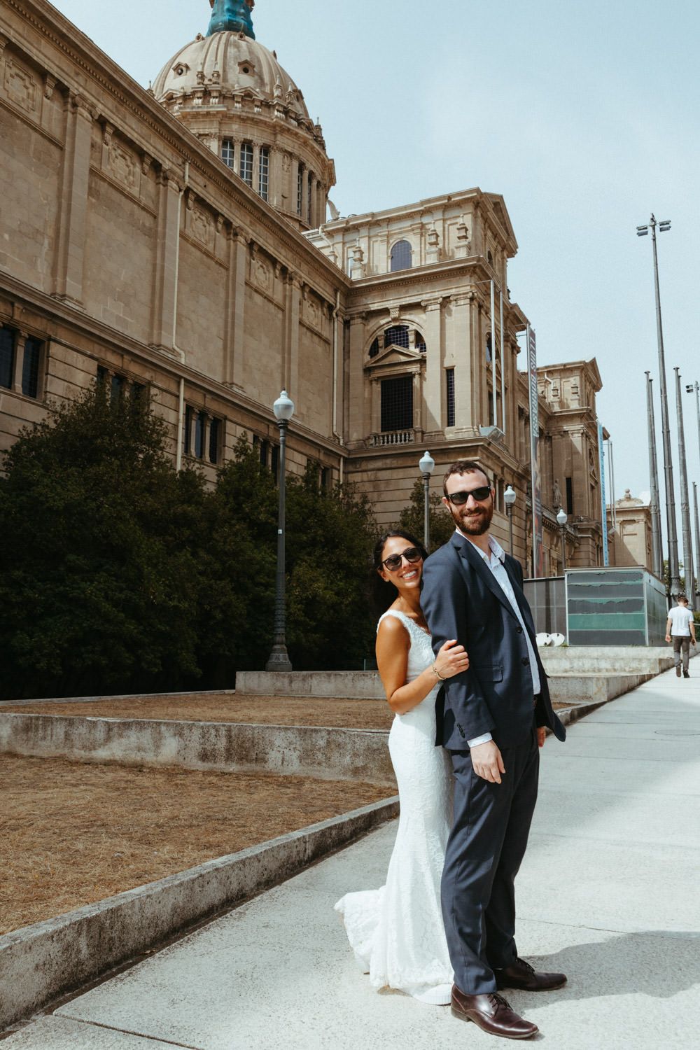 Couple poses playfully on grand stone steps in front of historic domed building.