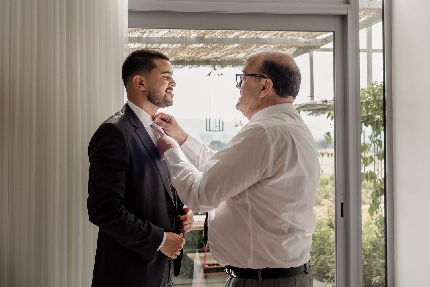 Two men in business attire stand near a doorway having an intense confrontation with one grabbing the other's collar.