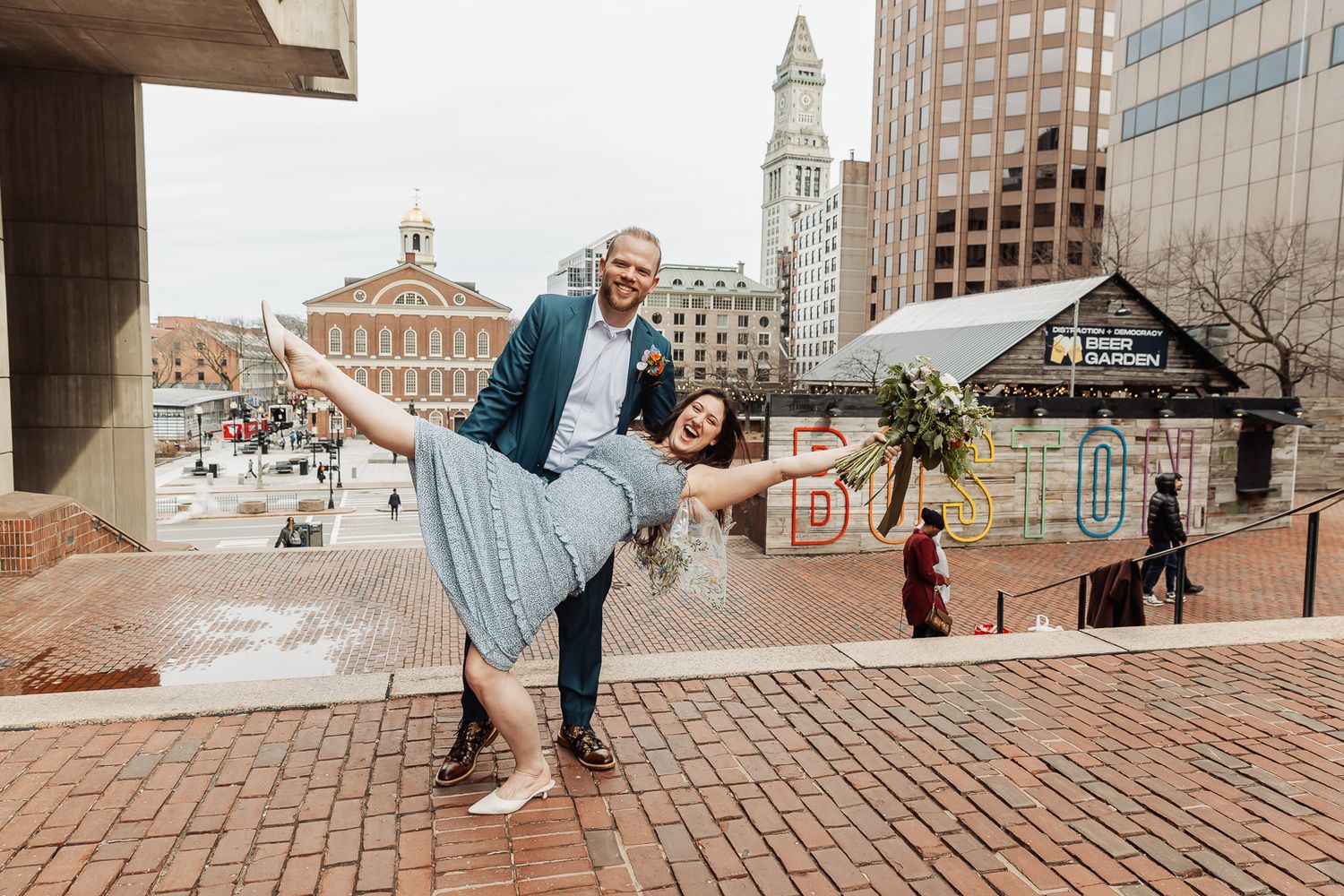 Couple dancing at Faneuil Hall Marketplace in Boston, man dipping woman in blue dress on brick plaza.
