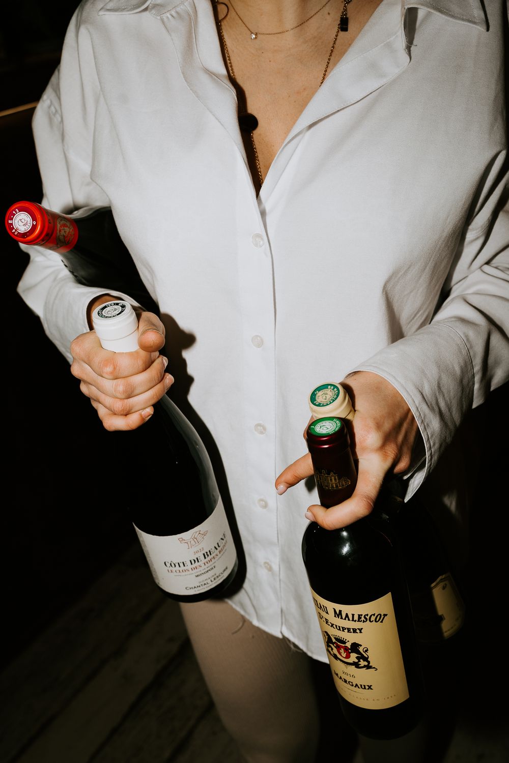 Femme en chemise blanche tenant des bouteilles de vin, photographe pour restaurant