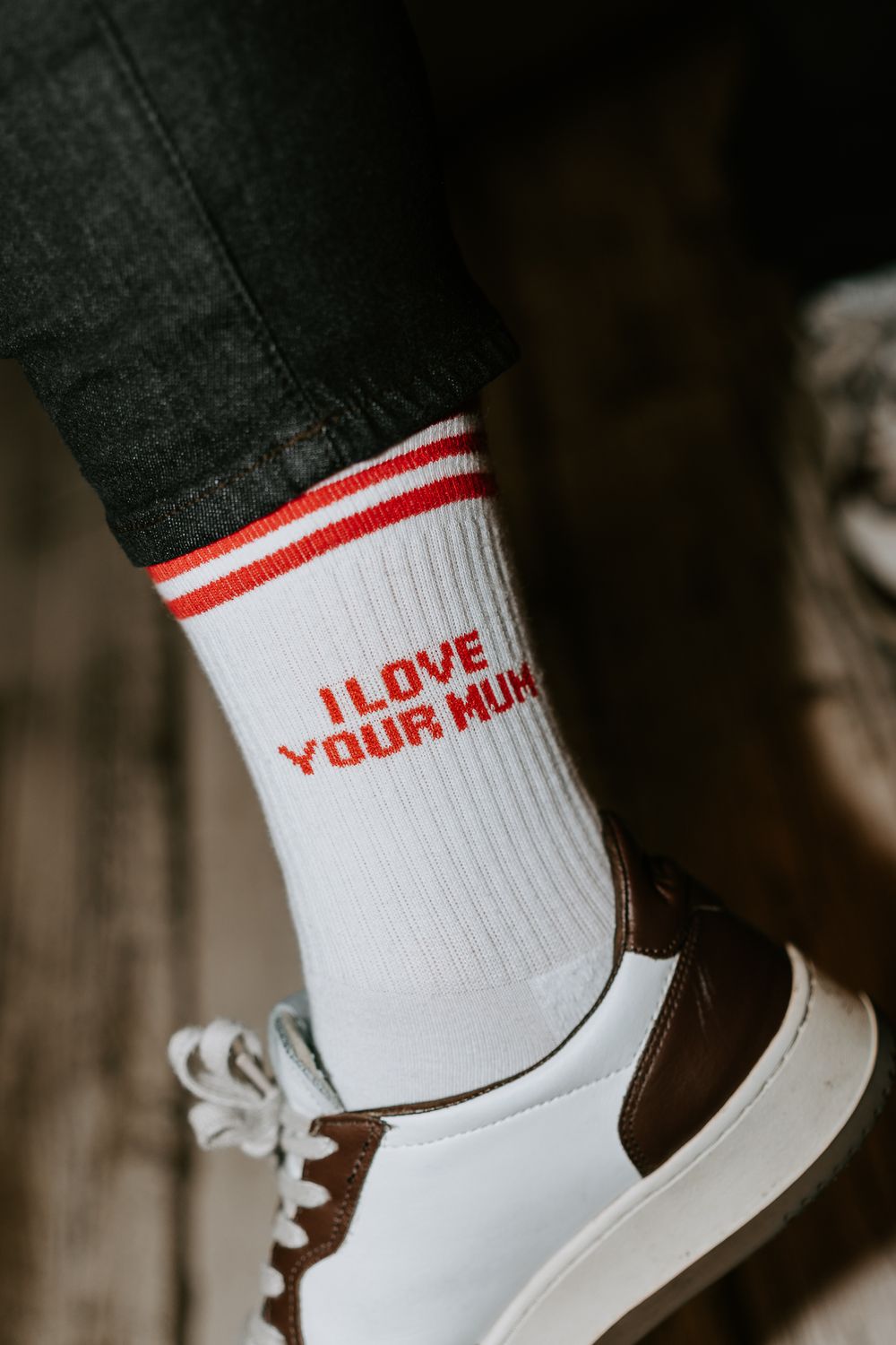 Chaussettes ras du cou côtelées blanches avec des rayures rouges et le texte "I Love Your Mum", portées avec des baskets marron et blanches.