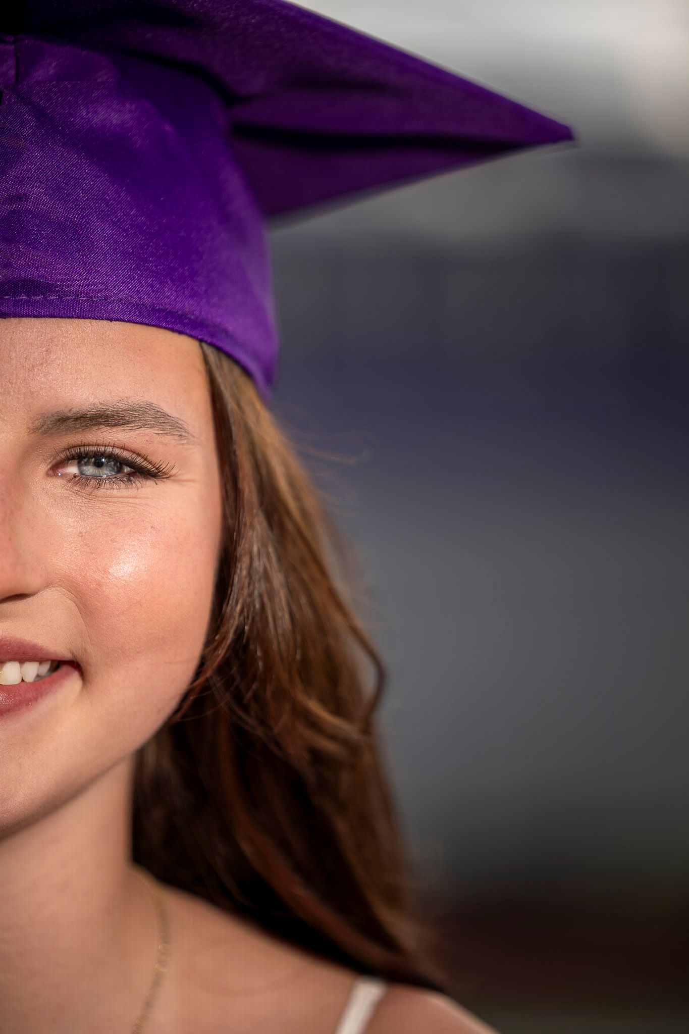 Young woman smiling in a purple graduation cap, celebrating her academic achievement.
