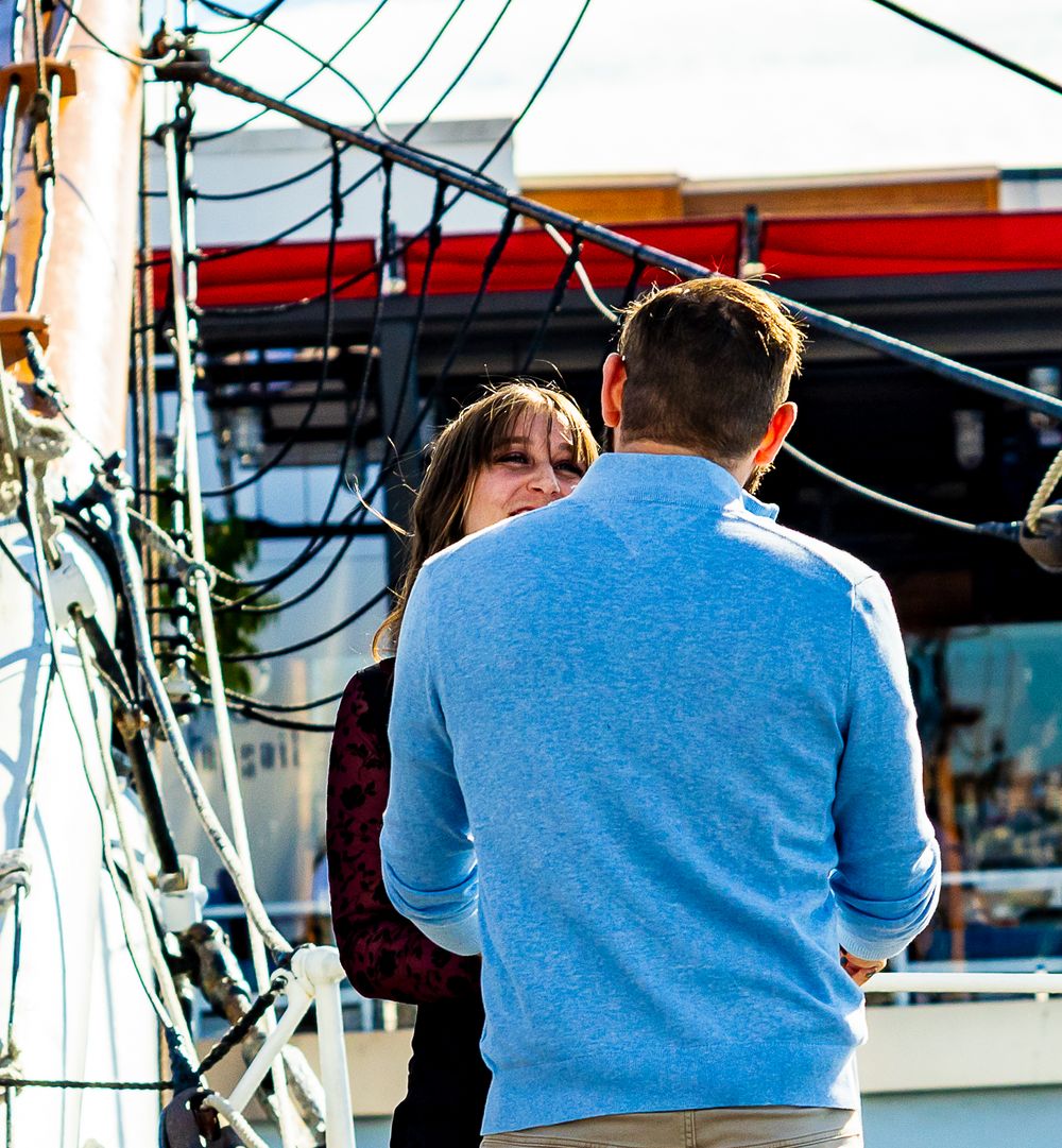 Couple gazing at the harbor from a sailing ship during an engagement session by Zeus Holbrook Wedding Photographer