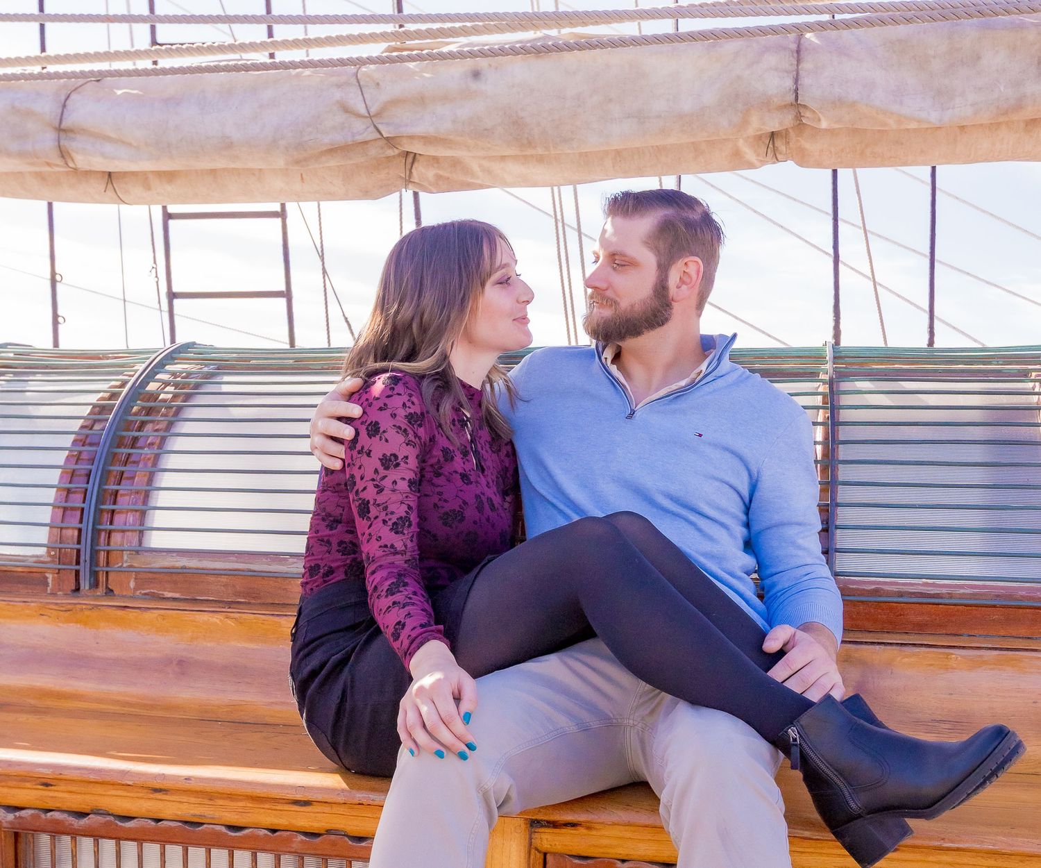Couple sitting together on a ship bench sharing a kiss during their engagement session by Zeus Holbrook Wedding Photographer
