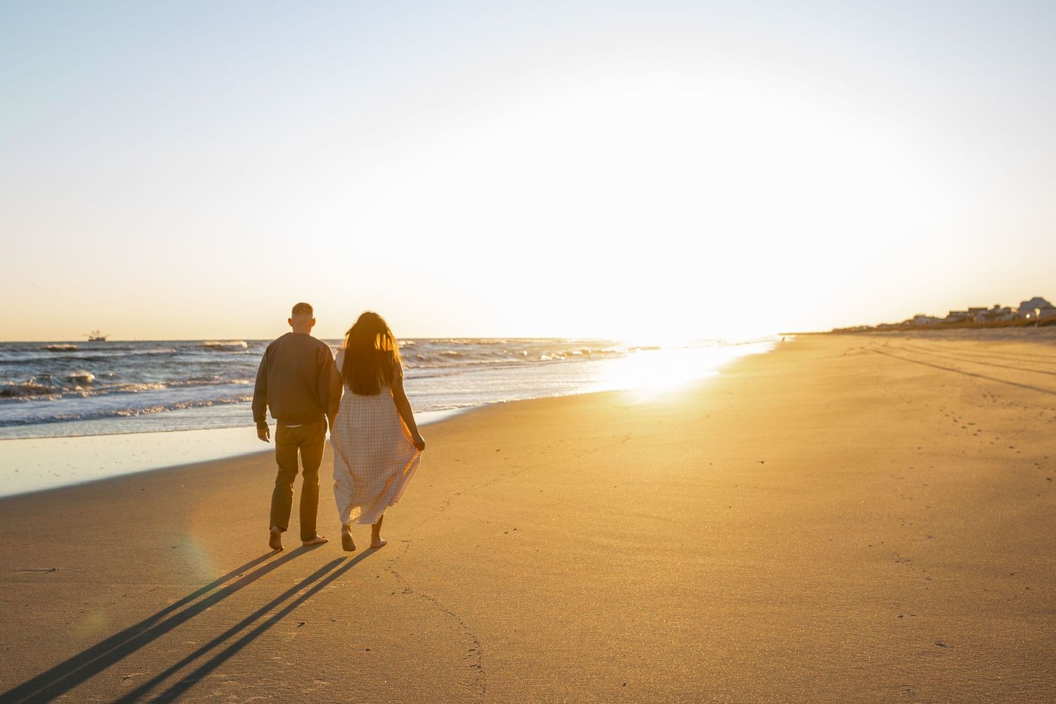 Beach maternity session on the Crystal Coast with an expecting mom walking along the shoreline in soft evening light near Swansboro, NC