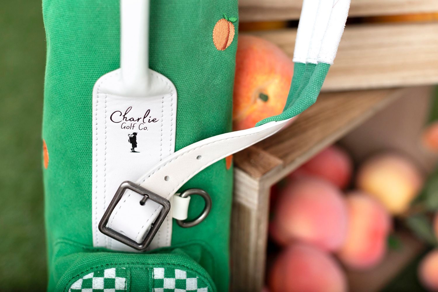 A white apron with green checkered pattern hangs on a hook near wooden shelves displaying fresh apples.