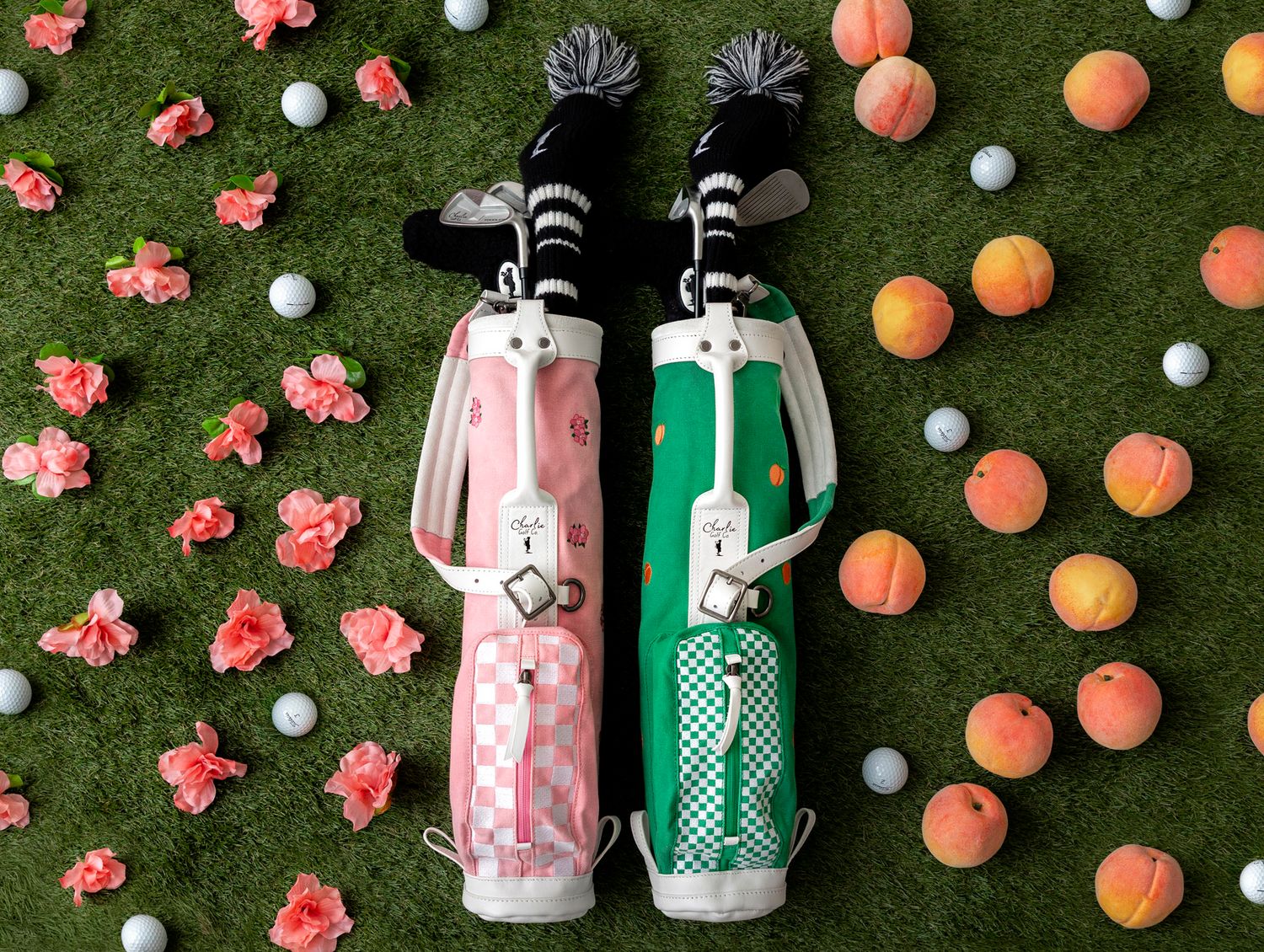 Pink and green golf bags with polka dot patterns surrounded by oranges and pink flowers on artificial grass.