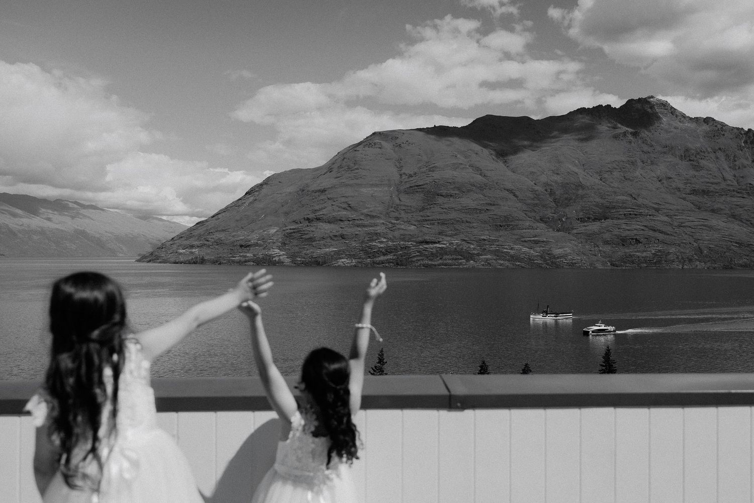A lakeside wedding ceremony showing Queenstown mountains and lake Wakatipu with flower girls at Rendezvous Heritage Hotel, New Zealand.