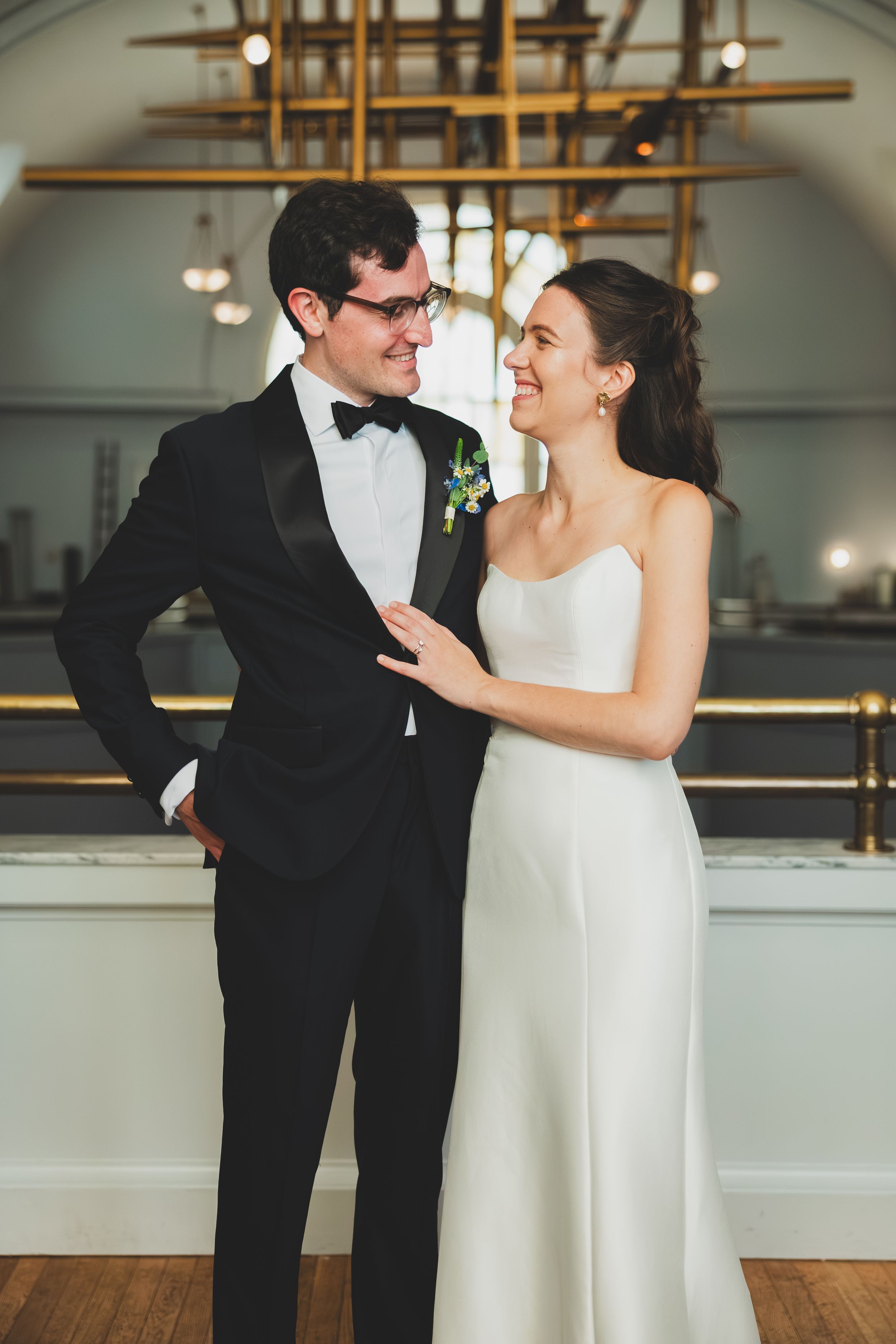A bride and groom share an intimate moment in a classic black and white wedding attire at an elegant indoor venue.